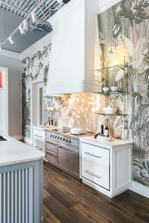 Silver base kitchen cabinet in between white cabinets and white custom kitchen hood above it